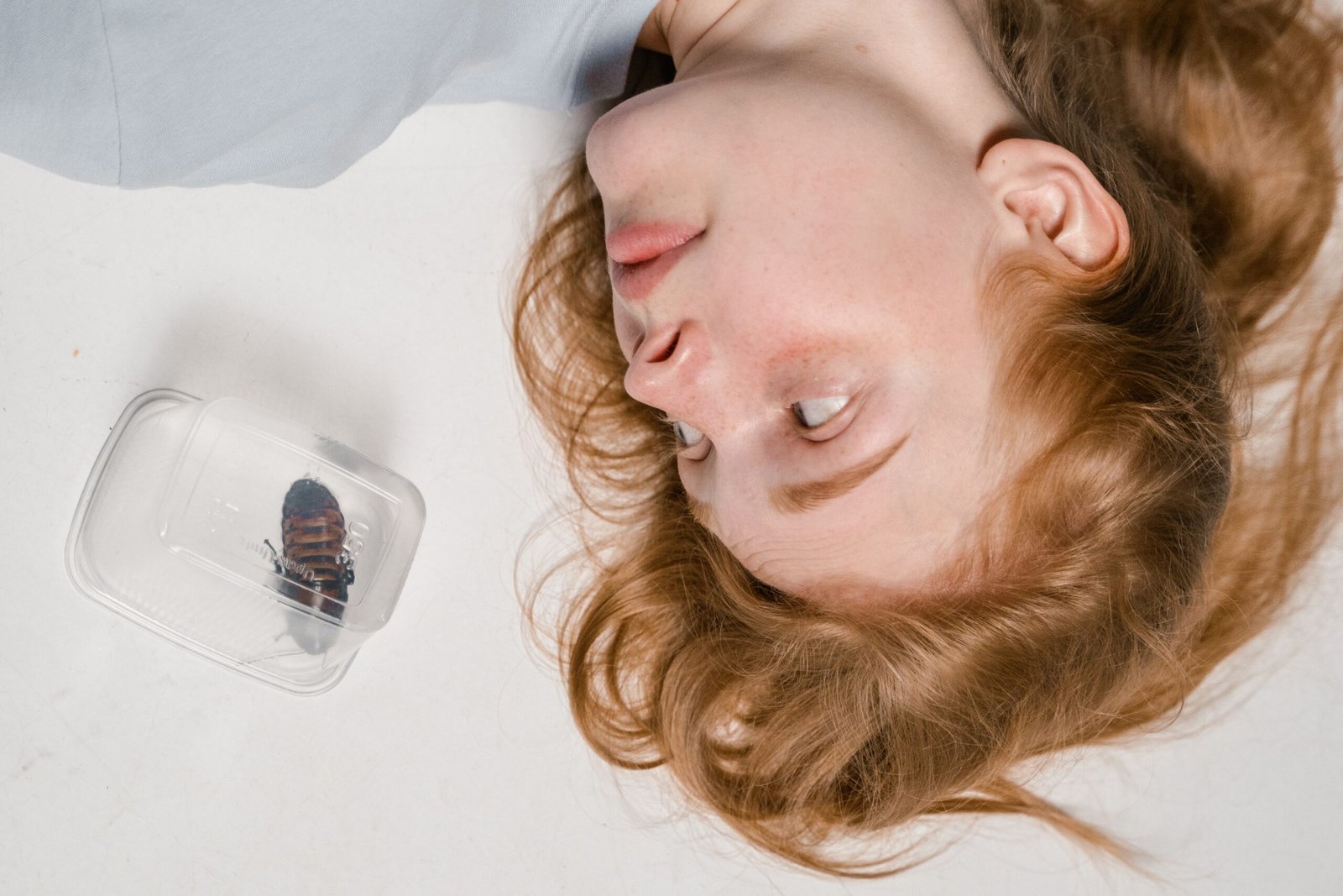 Woman lies near a container with a cockroach, symbolizing phobia or anxiety.